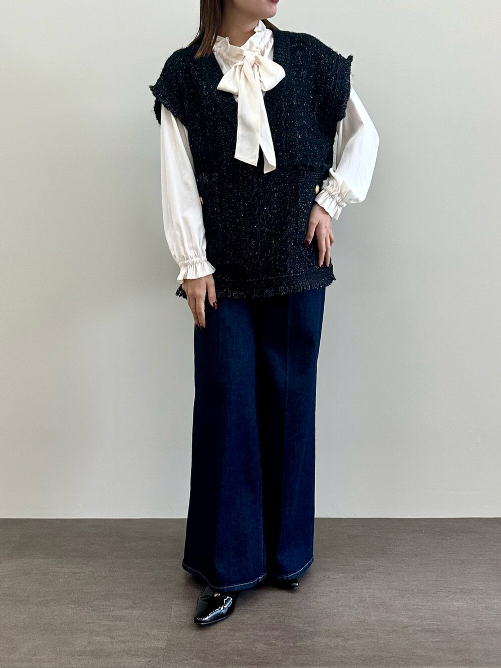 ブラック系のニット/セーター、ホワイト系のシャツ/ブラウス、ブルー系のデニムパンツを着用したレディースの夏コーディネートの2枚目の写真