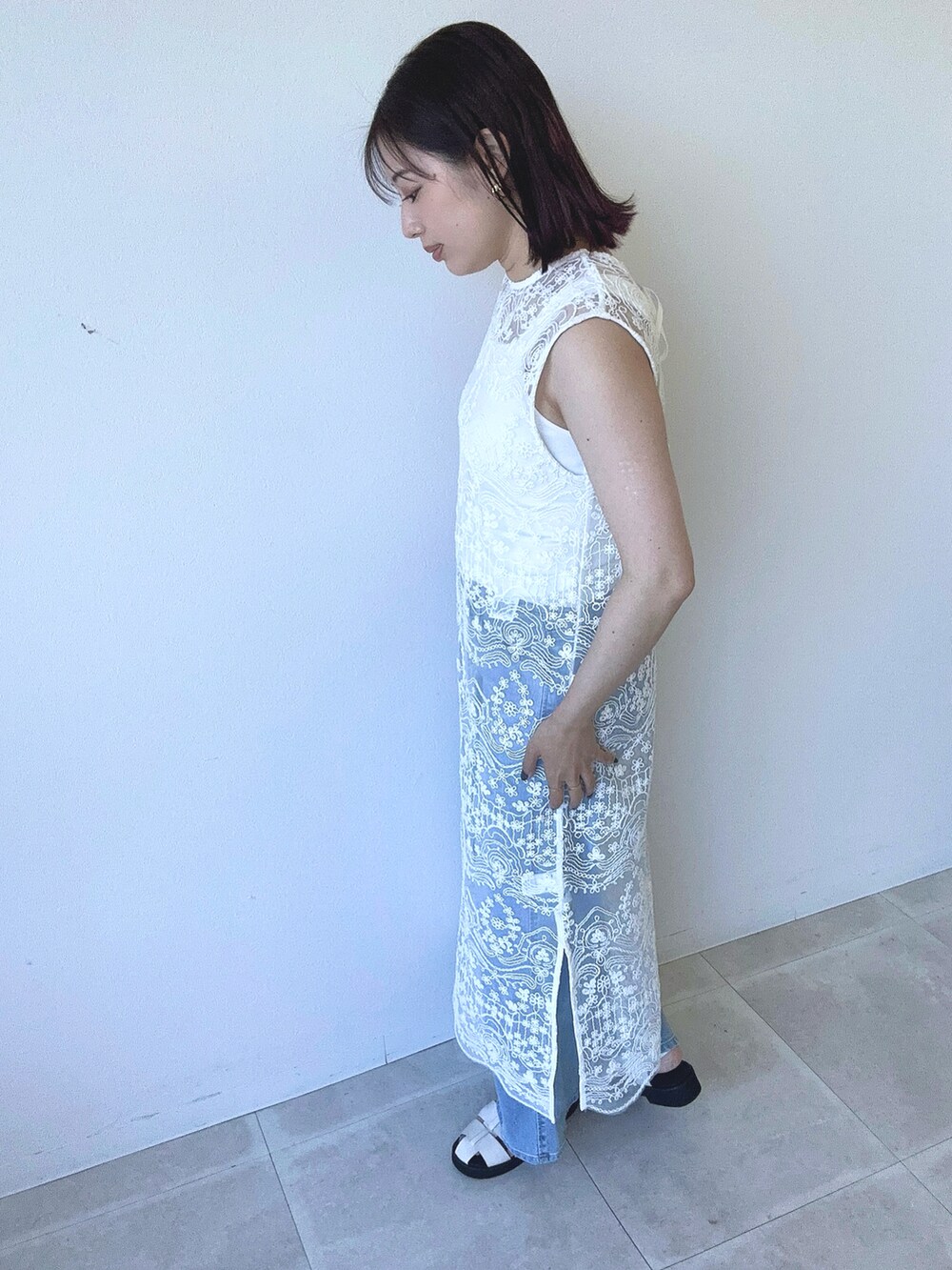 ホワイト系のワンピース、ホワイト系のタンクトップ、ブルー系のデニムパンツを着用したレディースの春コーディネートの2枚目の写真