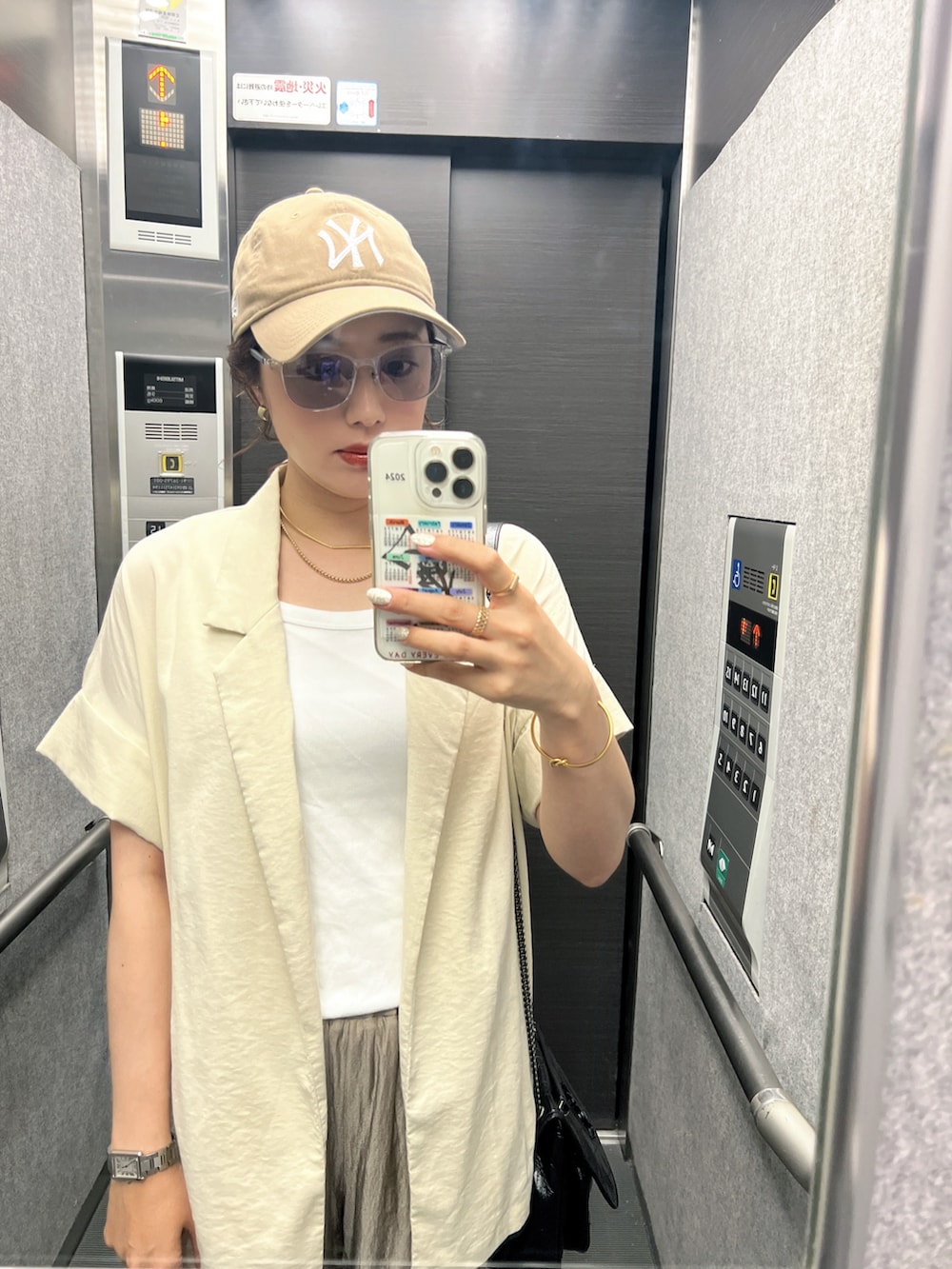 ホワイト系のタンクトップ、ベージュ系のテーラードジャケット、ベージュ系のパンツを着用したレディースの春コーディネートの2枚目の写真