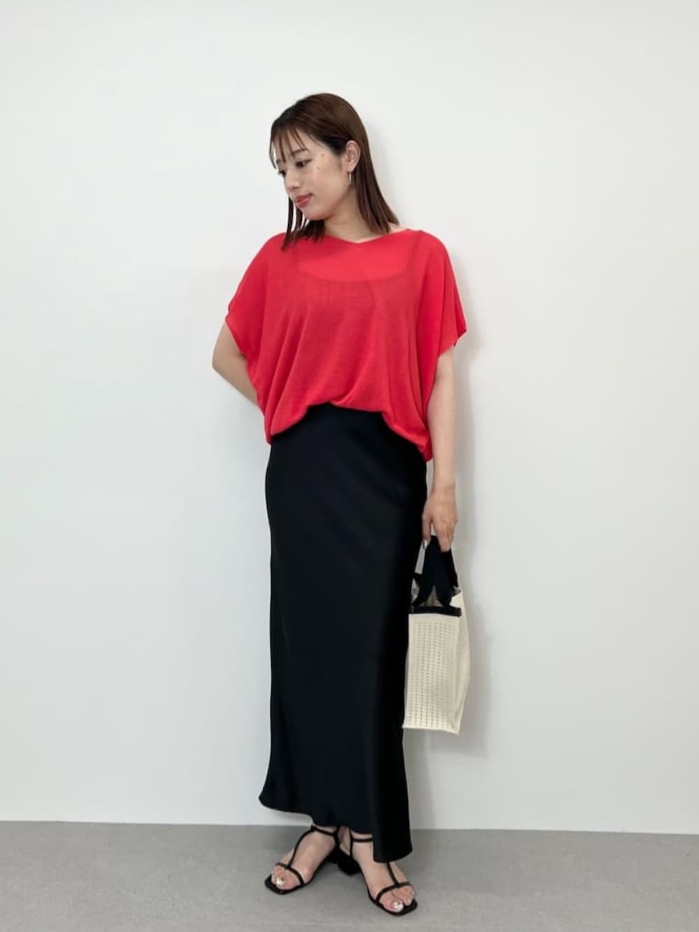 ピンク系のニット/セーター、ブラック系のスカート、ホワイト系のハンドバッグを着用したレディースの夏コーディネートの2枚目の写真