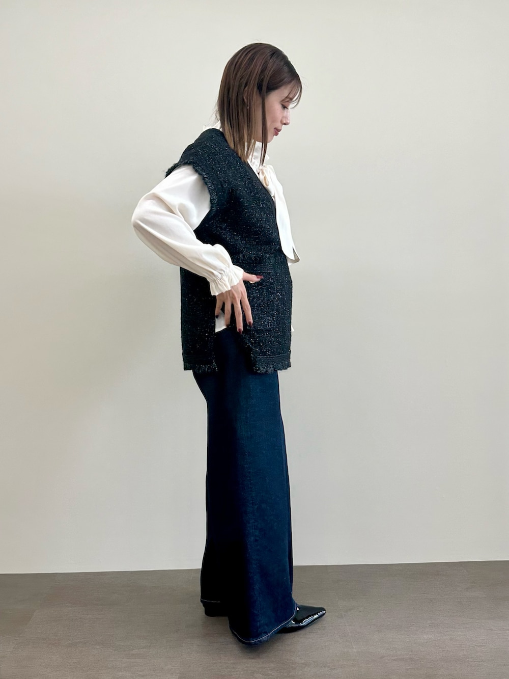 ブラック系のニット/セーター、ホワイト系のシャツ/ブラウス、ブルー系のデニムパンツを着用したレディースの夏コーディネートの4枚目の写真