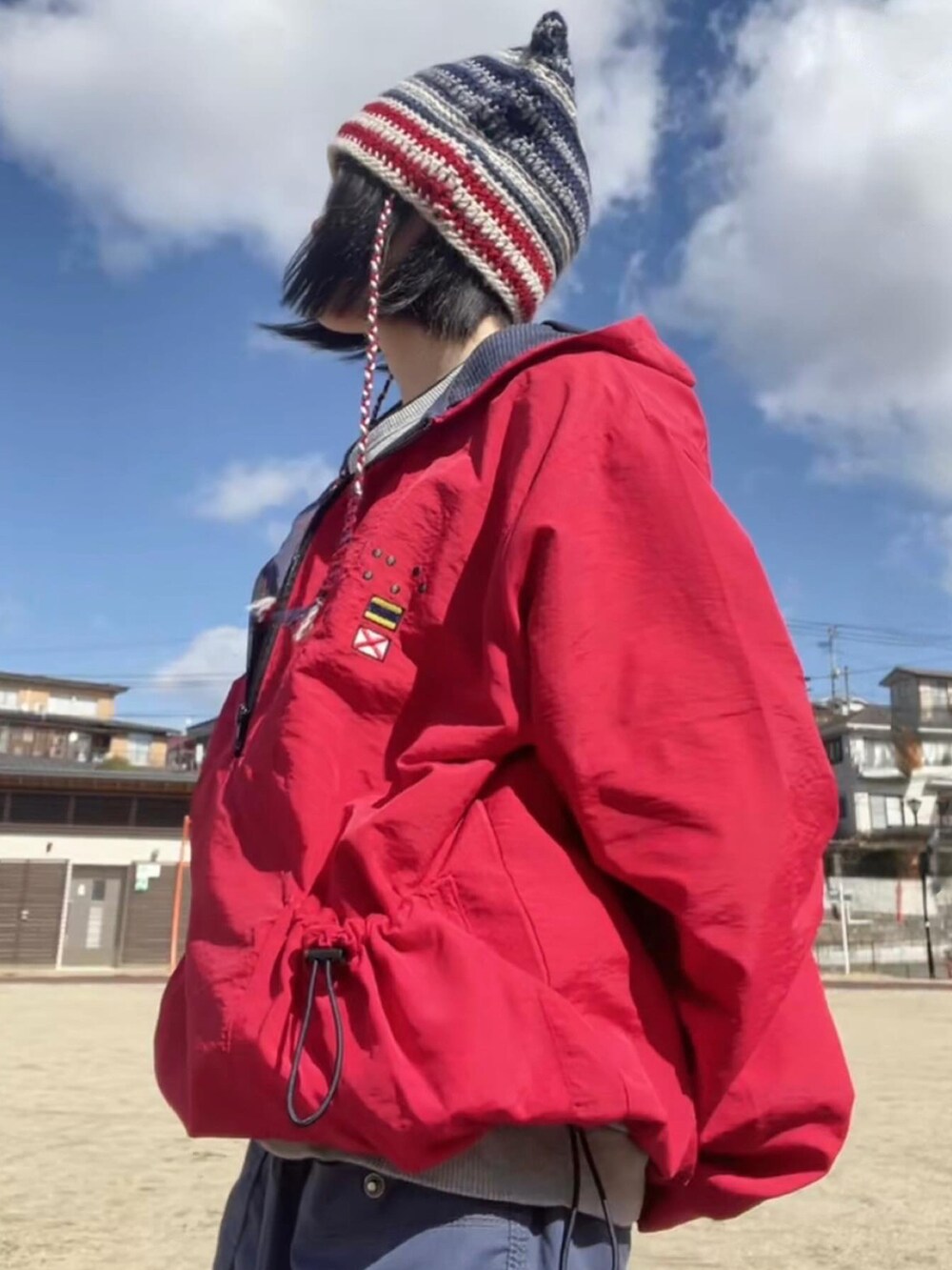 ブルー系のカーゴパンツ、レッド系のナイロンジャケット、グレー系のスウェットを着用したレディースの春コーディネートの4枚目の写真