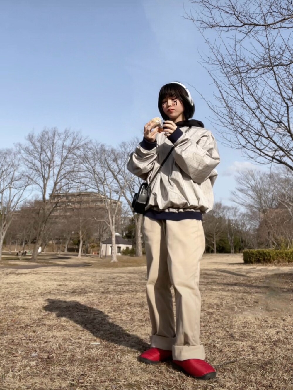レッド系のスリッポン、ベージュ系のパンツ、グレー系のナイロンジャケットを着用したレディースの春コーディネートの2枚目の写真