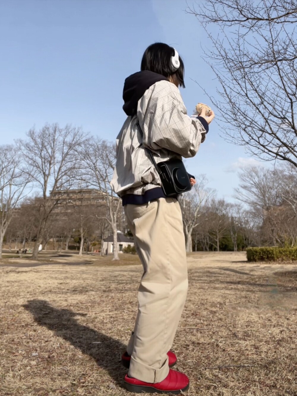 レッド系のスリッポン、ベージュ系のパンツ、グレー系のナイロンジャケットを着用したレディースの春コーディネートの3枚目の写真