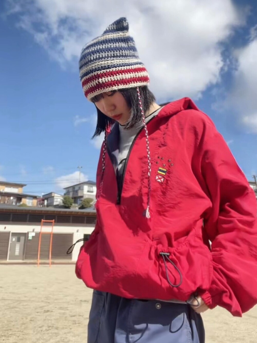 ブルー系のカーゴパンツ、レッド系のナイロンジャケット、グレー系のスウェットを着用したレディースの春コーディネートの2枚目の写真