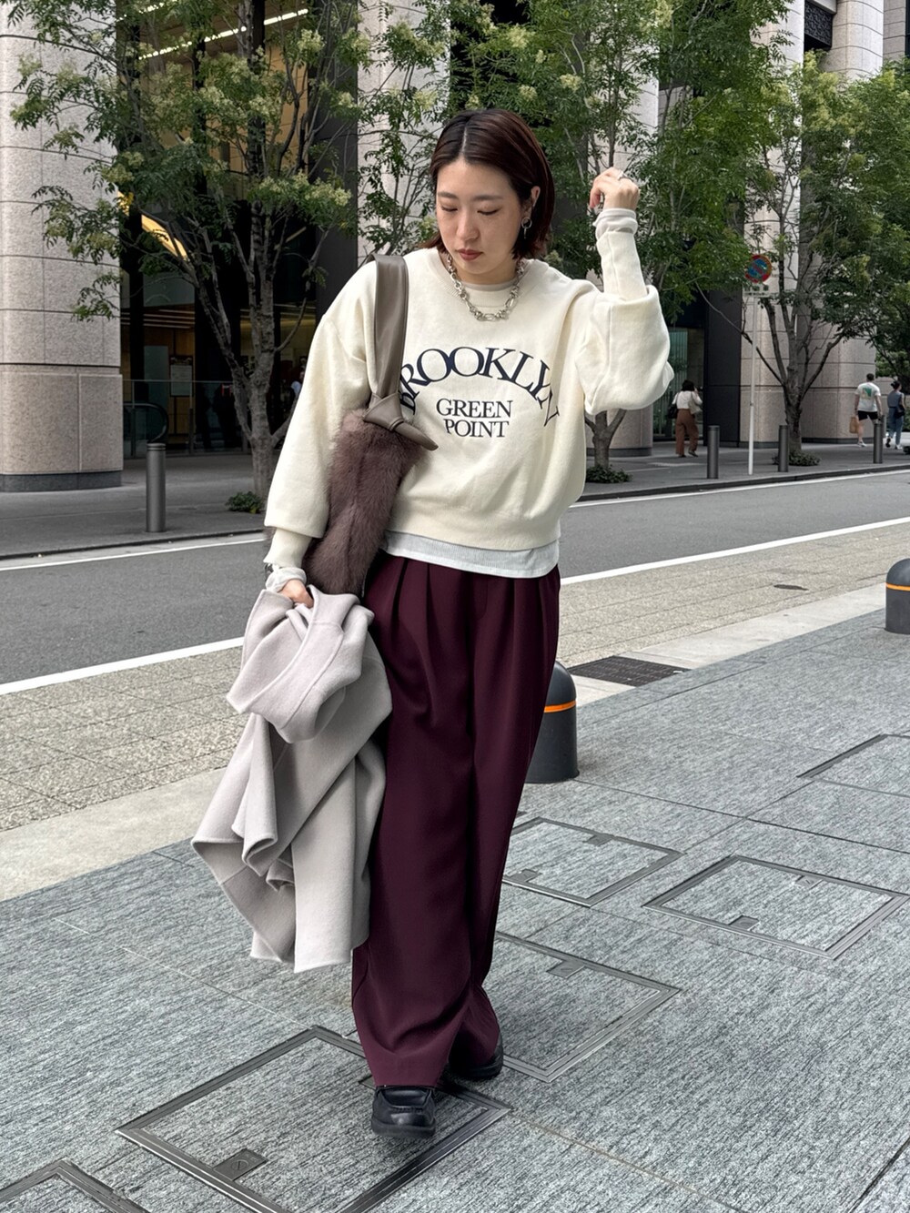 レッド系のスラックス、ベージュ系のその他アウター、ホワイト系のニット/セーターを着用したレディースの秋コーディネートの6枚目の写真