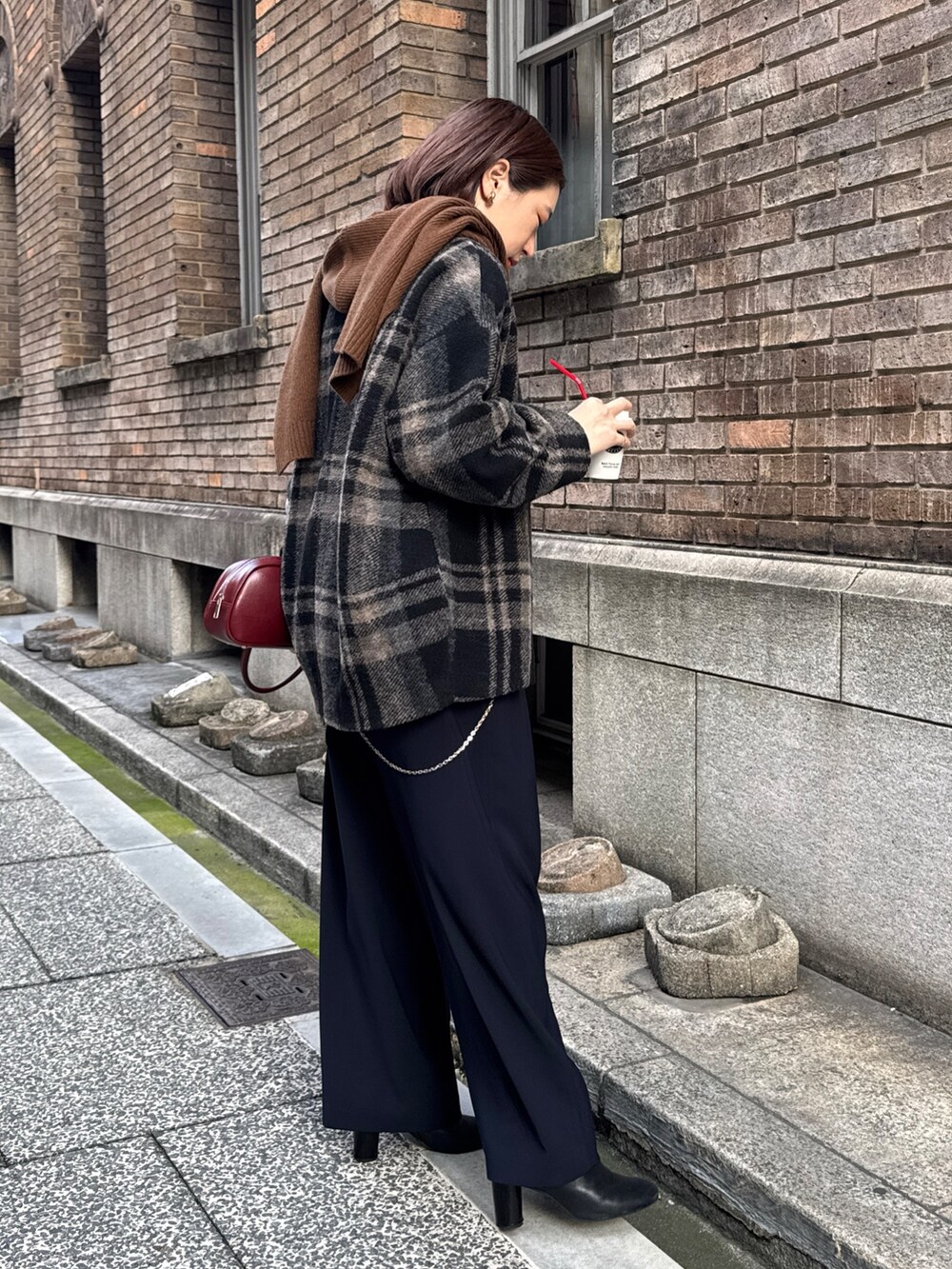 ブルー系のスラックス、ホワイト系のニット/セーター、レッド系のショルダーバッグを着用したレディースの秋コーディネートの2枚目の写真