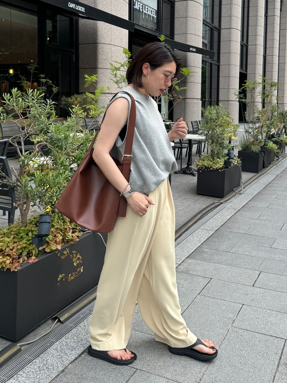 イエロー系のスラックス、グレー系のスウェット、シルバー系のベルトを着用したレディースの夏コーディネートの4枚目の写真