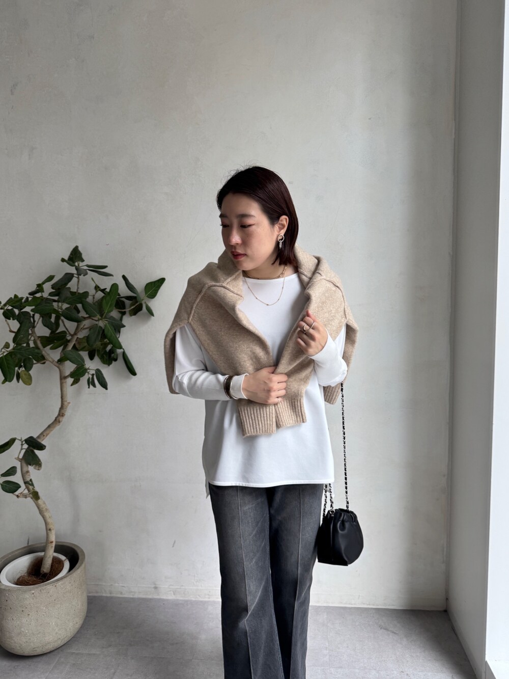 ブラック系のデニムパンツ、ベージュ系のニット/セーター、ホワイト系のTシャツ/カットソーを着用したレディースの秋コーディネートの8枚目の写真