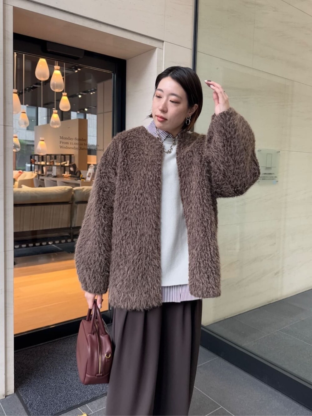 ブラウン系のスラックス、レッド系のシャツ/ブラウス、ブラウン系のショルダーバッグを着用したレディースの冬コーディネートの8枚目の写真