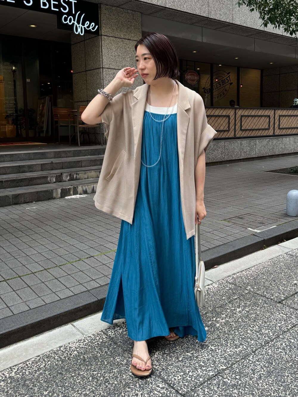 ベージュ系のテーラードジャケット、ホワイト系のタンクトップ、ブルー系のワンピースを着用したレディースの夏コーディネートの2枚目の写真