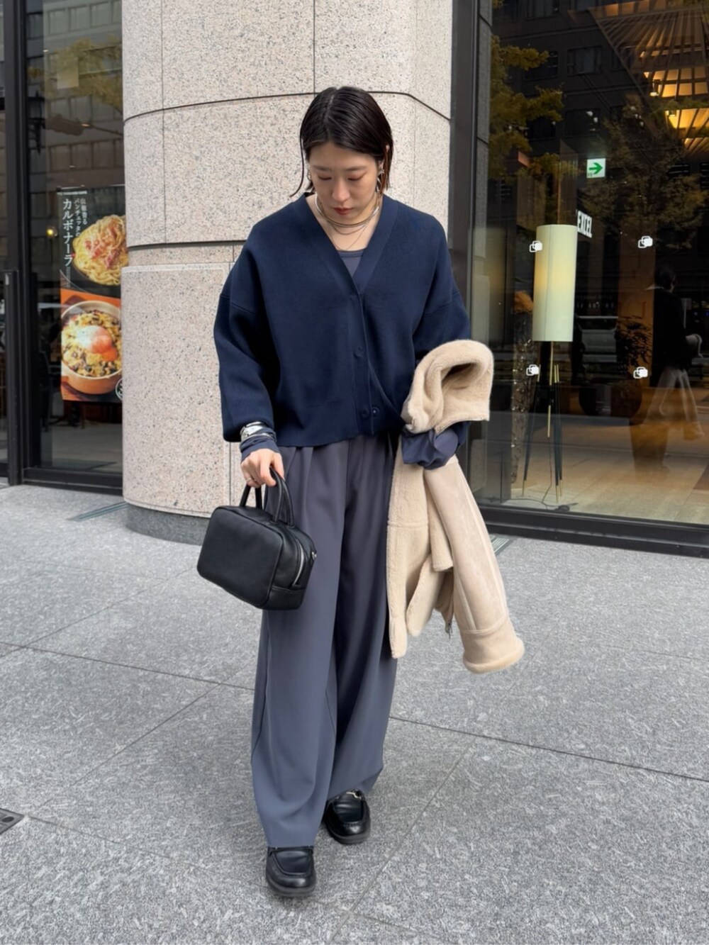 グレー系のスラックス、ブラック系のショルダーバッグ、ベージュ系のその他アウターを着用したレディースの冬コーディネートの3枚目の写真