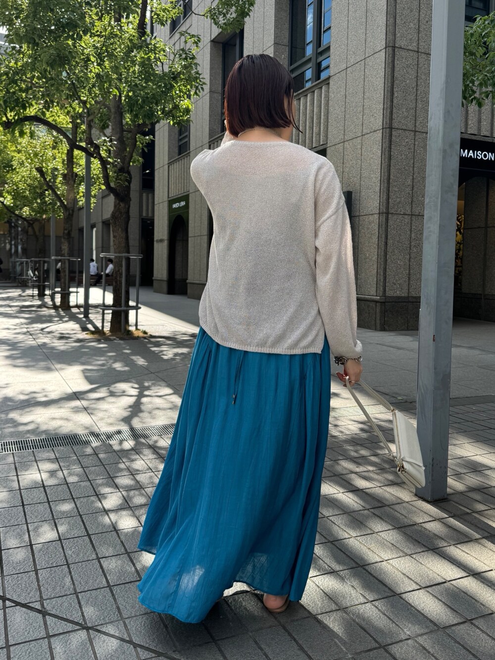 ブルー系のワンピース、ベージュ系のニット/セーター、ホワイト系のショルダーバッグを着用したレディースの夏コーディネートの7枚目の写真