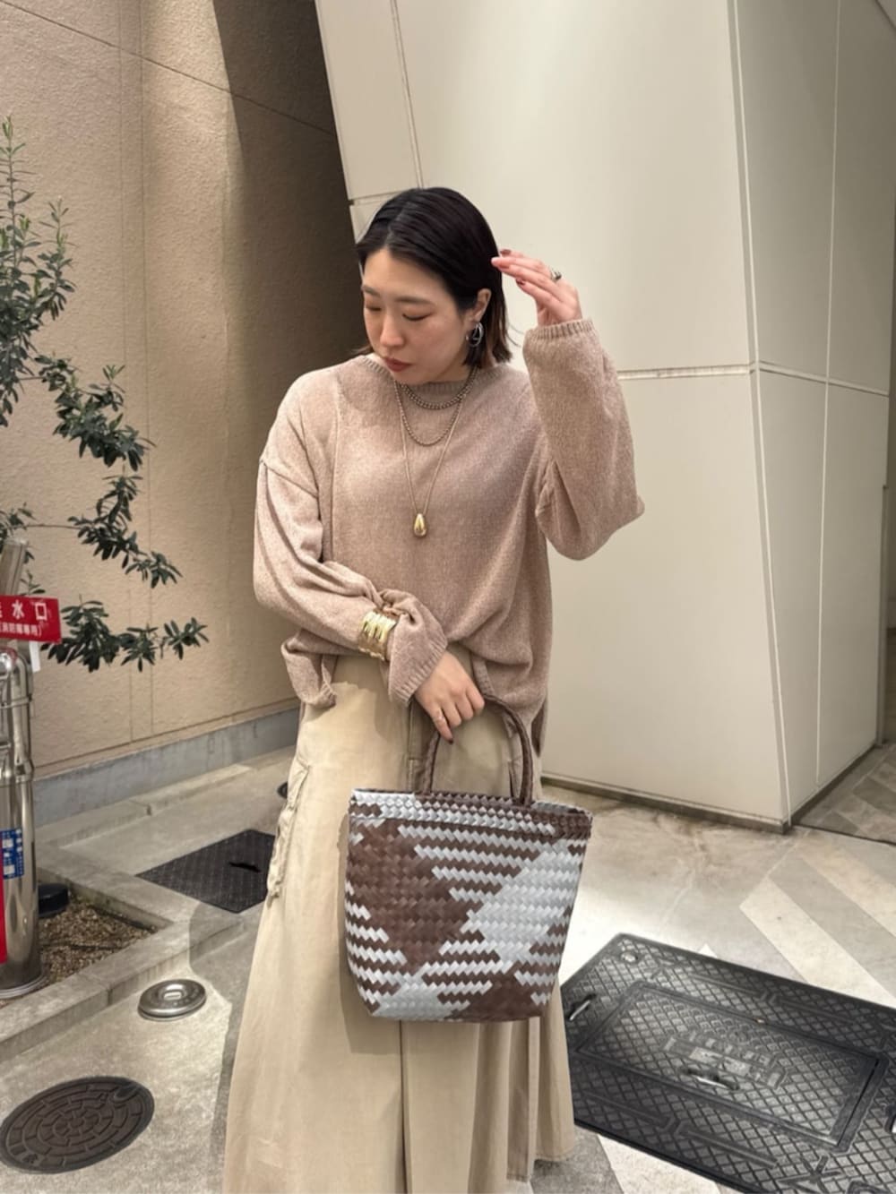 ベージュ系のスカート、ゴールド系のネックレスを着用したレディースの春コーディネートの2枚目の写真