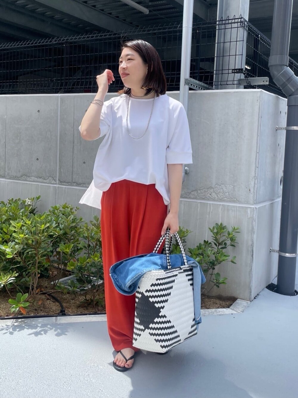 ホワイト系のシャツ/ブラウス、オレンジ系のスラックス、ホワイト系のかごバッグを着用したレディースの夏コーディネートの5枚目の写真