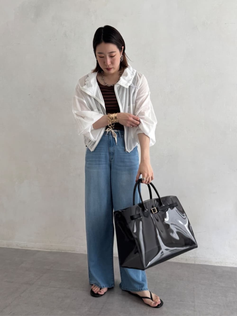 ブラック系のショルダーバッグ、ブルー系のデニムパンツ、ブラウン系のニット/セーターを着用したレディースの夏コーディネートの8枚目の写真