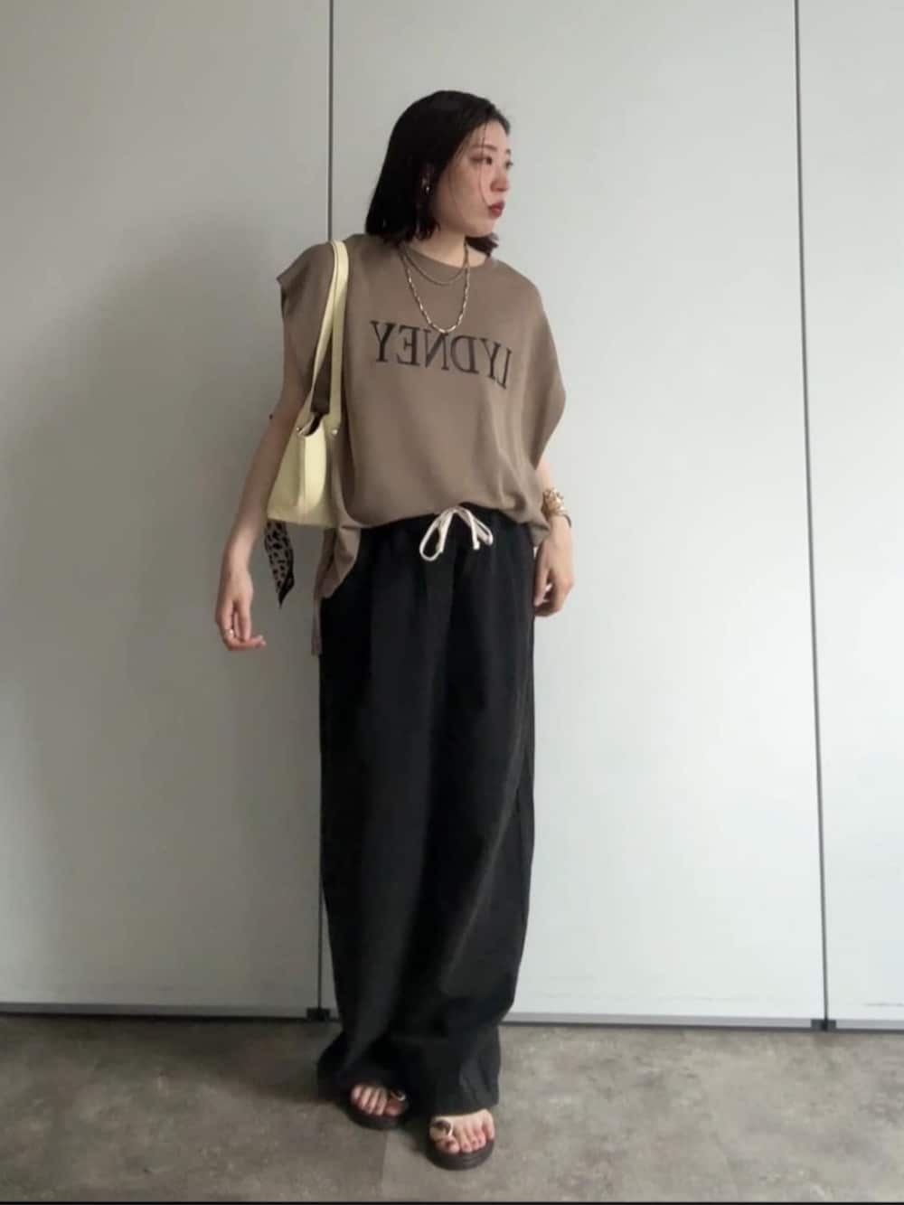イエロー系のショルダーバッグ、ブラウン系のサンダル、ブラック系のデニムパンツを着用したレディースの夏コーディネートの6枚目の写真