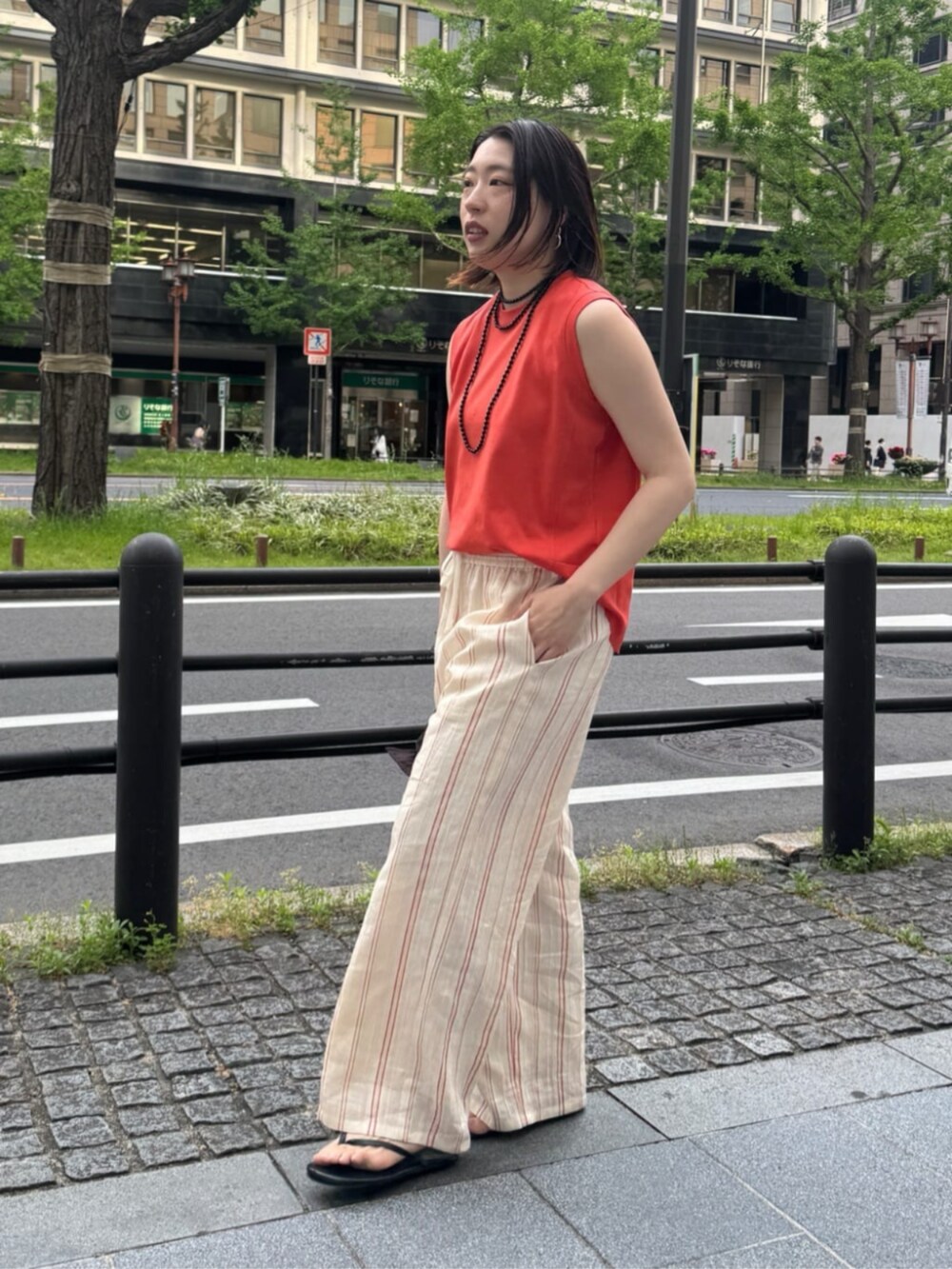 ブラック系のショルダーバッグ、オレンジ系のTシャツ/カットソー、ベージュ系のその他パンツを着用したレディースの夏コーディネートの5枚目の写真