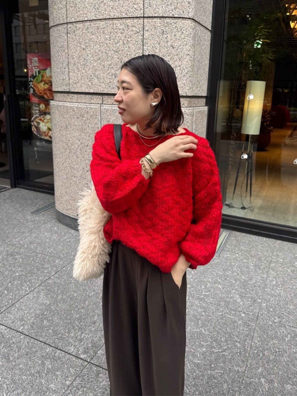 ブラウン系のスラックス、ホワイト系のショルダーバッグ、レッド系のニット/セーターを着用したレディースの秋コーディネートの4枚目の写真