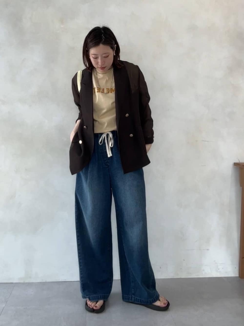 ブルー系のデニムパンツ、イエロー系のショルダーバッグ、ベージュ系のTシャツ/カットソーを着用したレディースの夏コーディネートの4枚目の写真