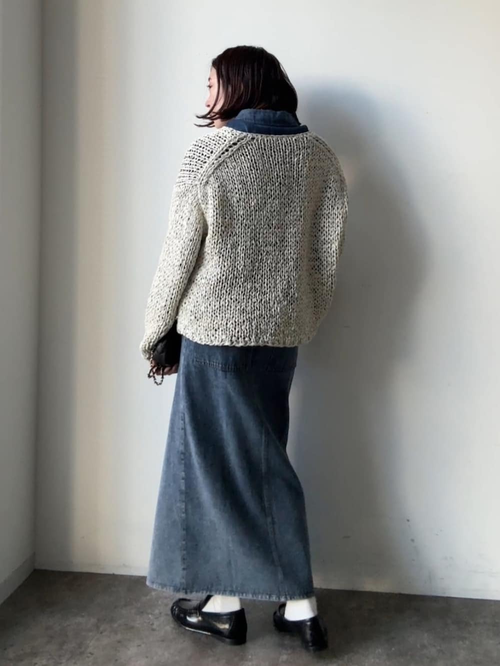 グレー系のニット/セーター、ブルー系のスカート、ブルー系のシャツ/ブラウスを着用したレディースの冬コーディネートの2枚目の写真