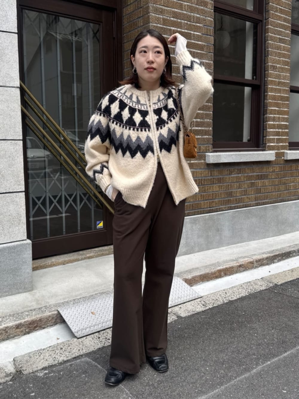 イエロー系のショルダーバッグ、ホワイト系のカーディガン/ボレロ、ブラウン系のその他パンツを着用したレディースの冬コーディネートの2枚目の写真