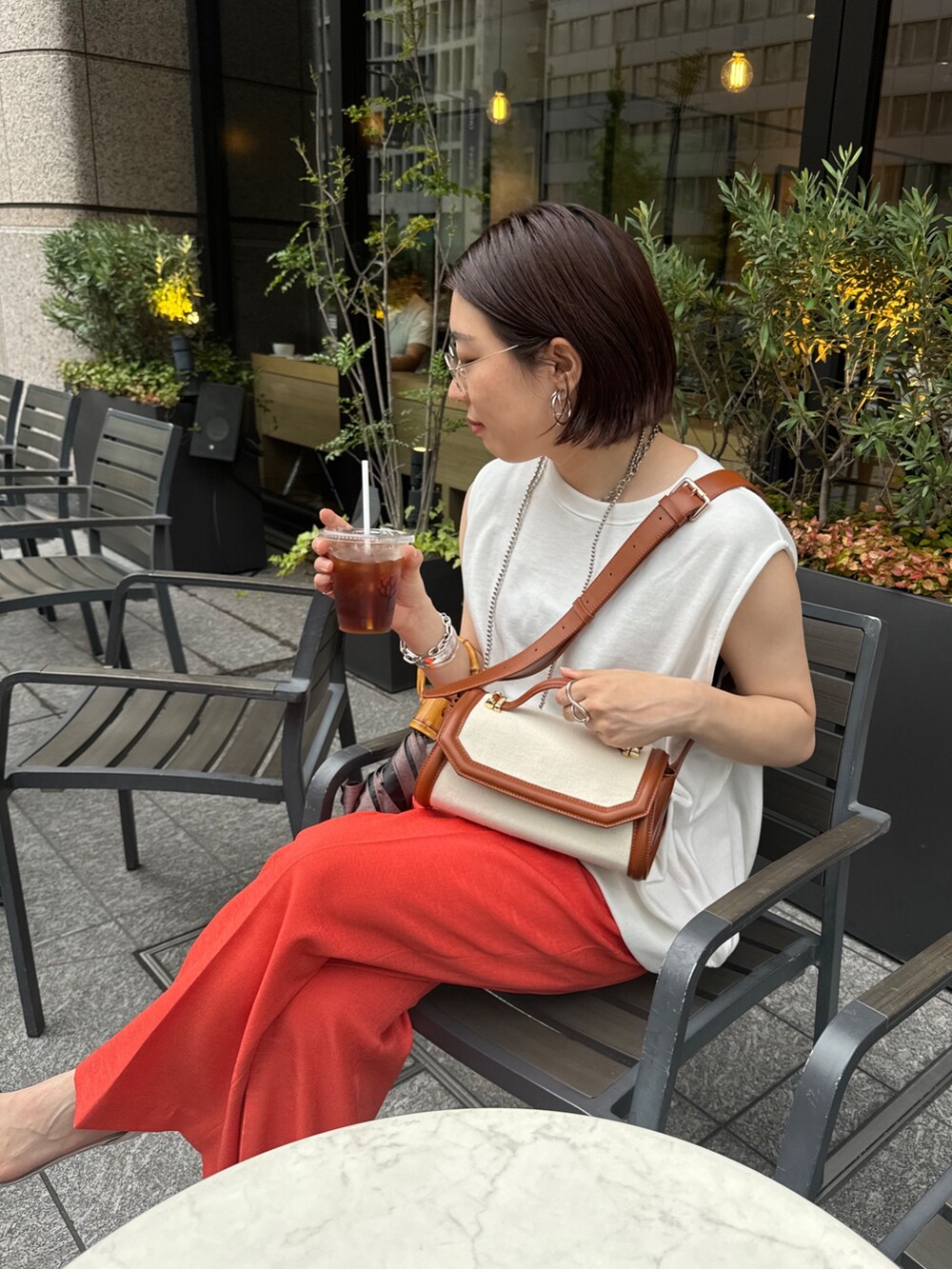 オレンジ系のその他パンツ、ホワイト系のスウェット、ブラウン系のショルダーバッグを着用したレディースの夏コーディネートの4枚目の写真