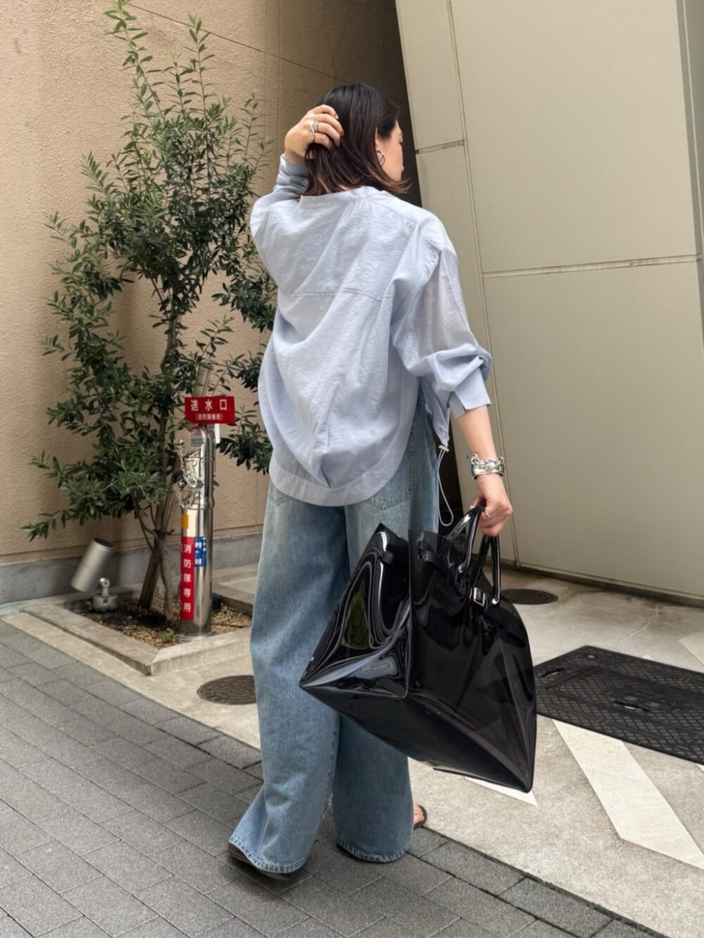 ホワイト系のタンクトップ、ブラック系のショルダーバッグ、ブルー系のデニムパンツを着用したレディースの春コーディネートの4枚目の写真