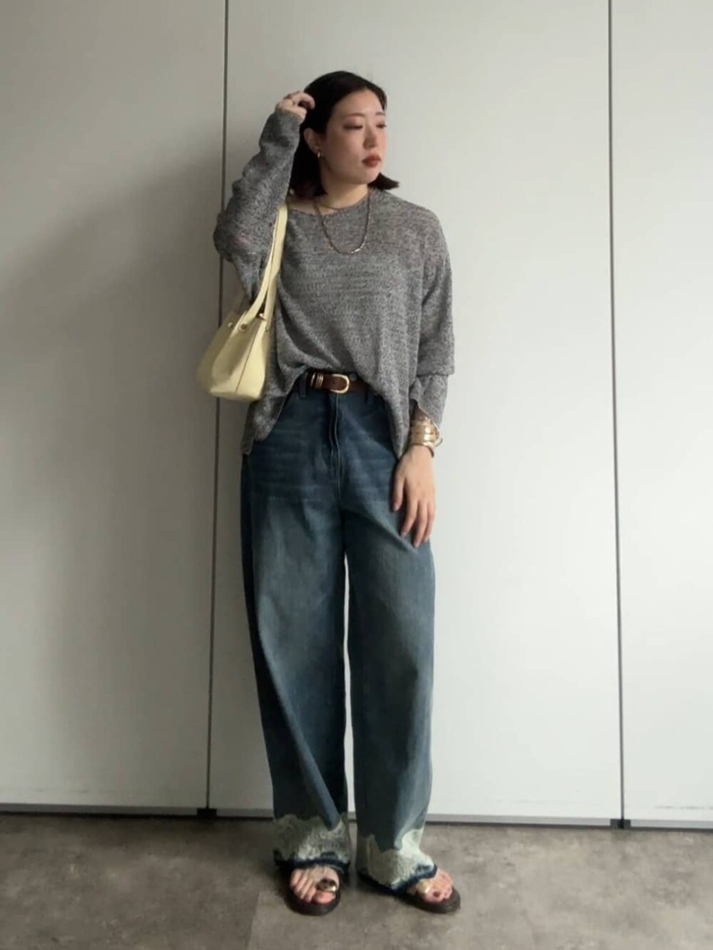 ブラック系のニット/セーター、イエロー系のショルダーバッグ、ブルー系のデニムパンツを着用したレディースの夏コーディネートの3枚目の写真