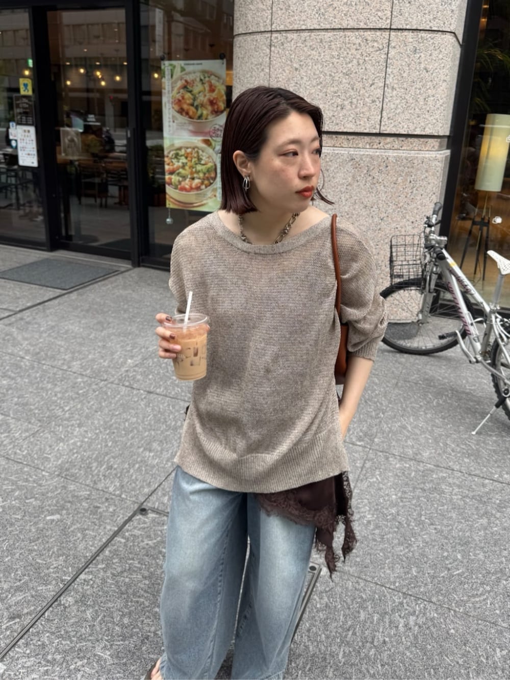 ブルー系のデニムパンツ、ブラウン系のキャミソール、ベージュ系のカーディガン/ボレロを着用したレディースの春コーディネートの2枚目の写真