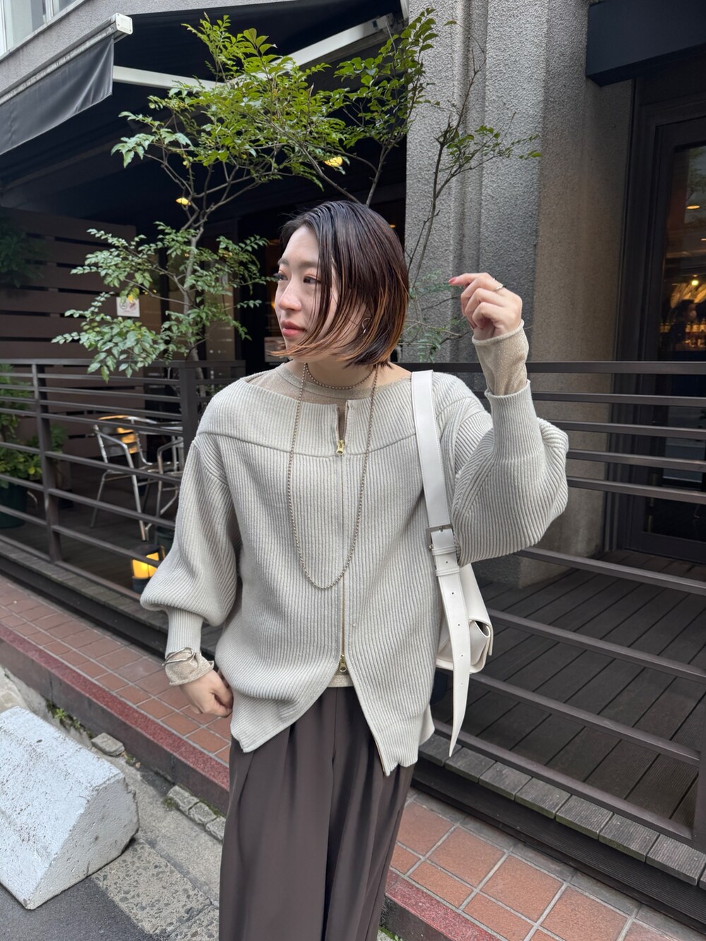 グレー系のニット/セーター、ブラウン系のスラックス、ゴールド系のTシャツ/カットソーを着用したレディースの冬コーディネートの6枚目の写真