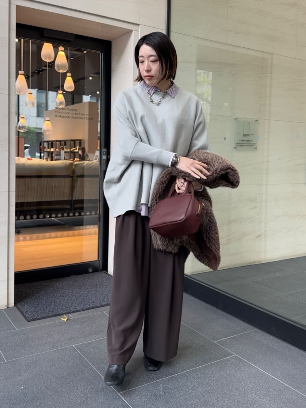 ブラウン系のスラックス、レッド系のシャツ/ブラウス、ブラウン系のショルダーバッグを着用したレディースの冬コーディネートの3枚目の写真