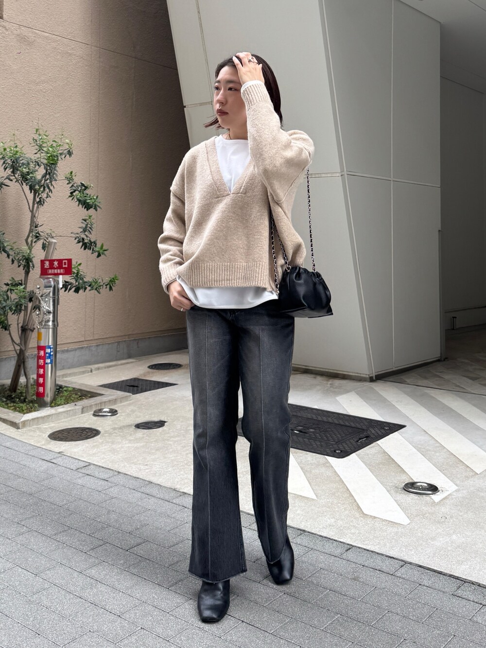 ブラック系のデニムパンツ、ベージュ系のニット/セーター、ホワイト系のTシャツ/カットソーを着用したレディースの秋コーディネートの2枚目の写真