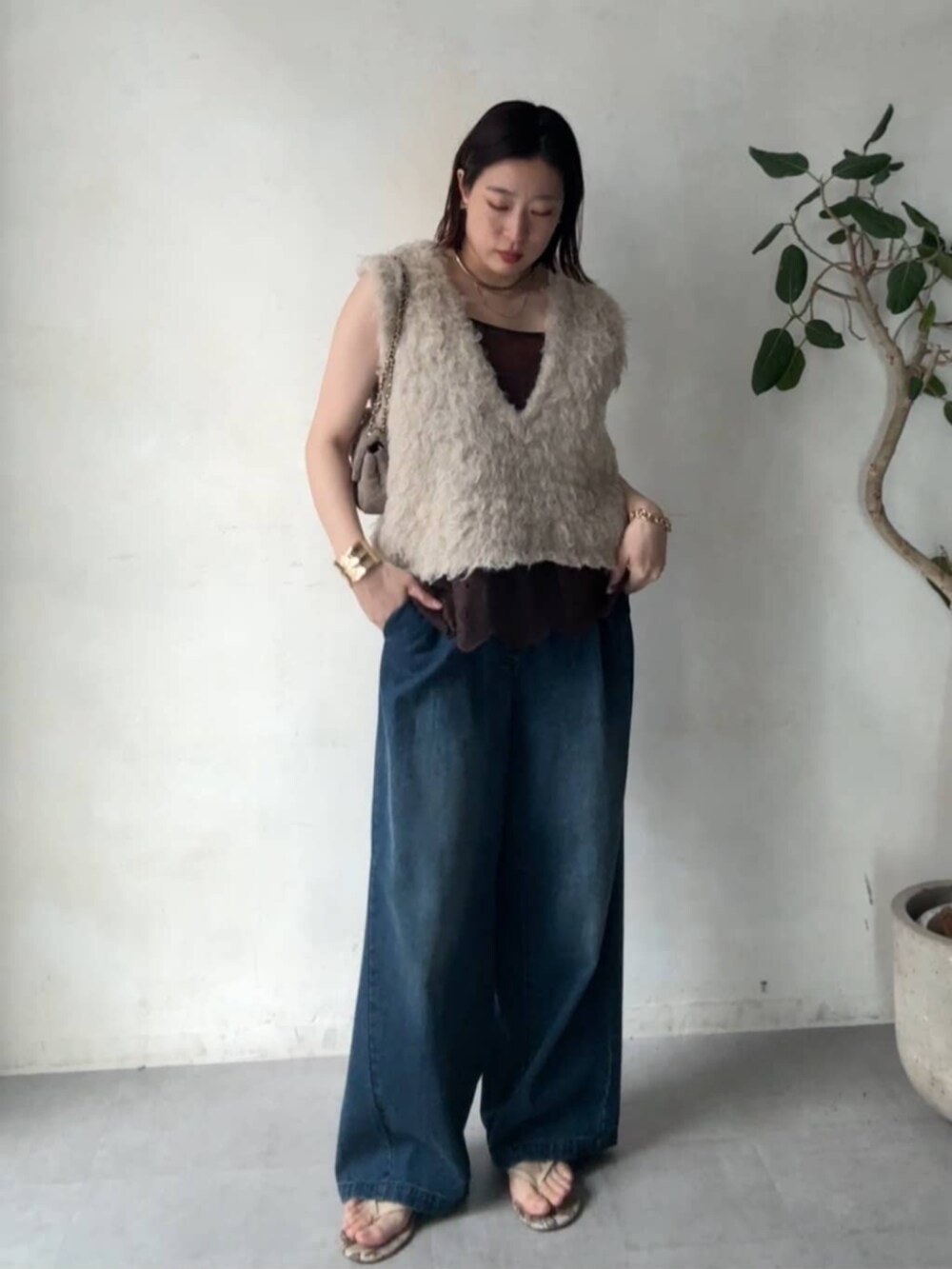 グレー系のショルダーバッグ、ベージュ系のニット/セーター、ブルー系のデニムパンツを着用したレディースの秋コーディネートの5枚目の写真