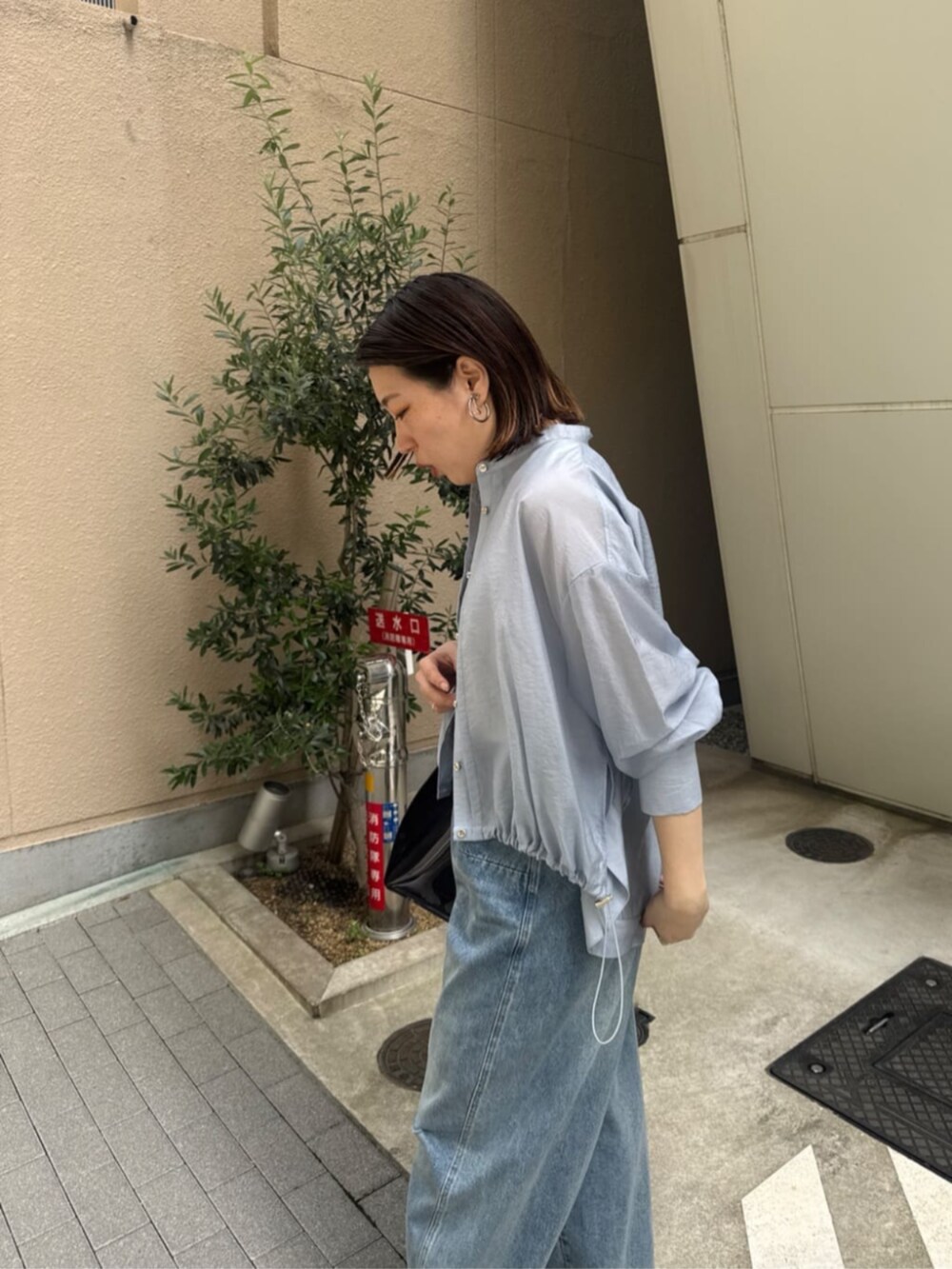 ホワイト系のタンクトップ、ブラック系のショルダーバッグ、ブルー系のデニムパンツを着用したレディースの春コーディネートの2枚目の写真