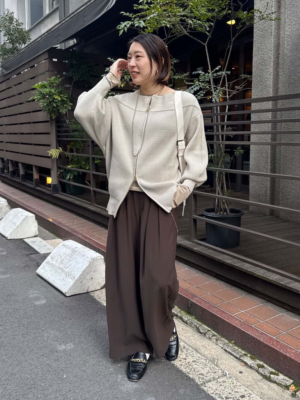 グレー系のニット/セーター、ブラウン系のスラックス、ゴールド系のTシャツ/カットソーを着用したレディースの冬コーディネートの7枚目の写真