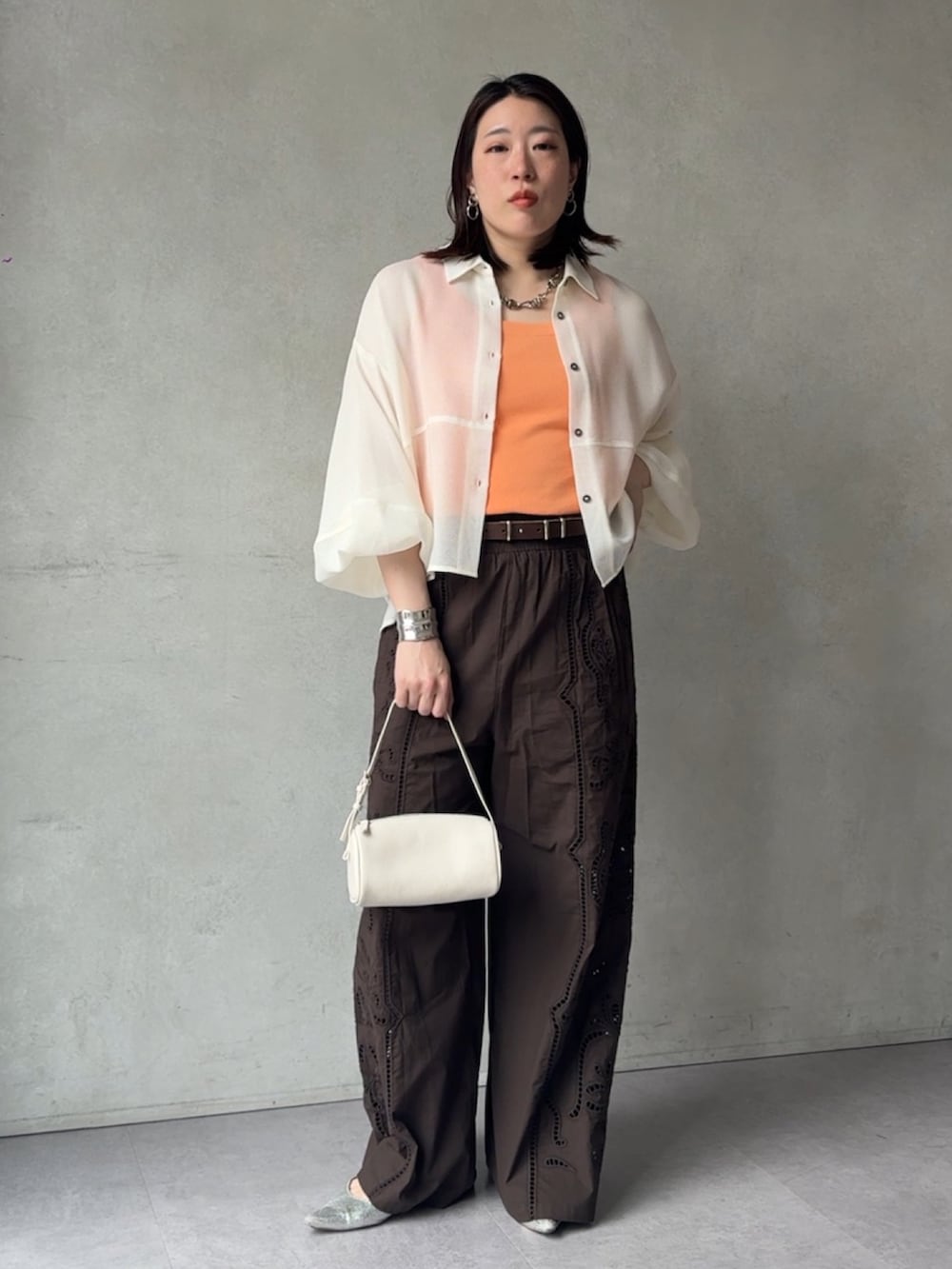 ブラウン系のその他パンツ、ホワイト系のシャツ/ブラウス、オレンジ系のニット/セーターを着用したレディースの春コーディネートの5枚目の写真