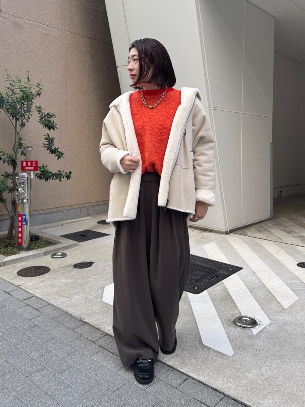 ブラウン系のスラックス、ホワイト系のその他アウター、ホワイト系のショルダーバッグを着用したレディースの秋コーディネートの2枚目の写真