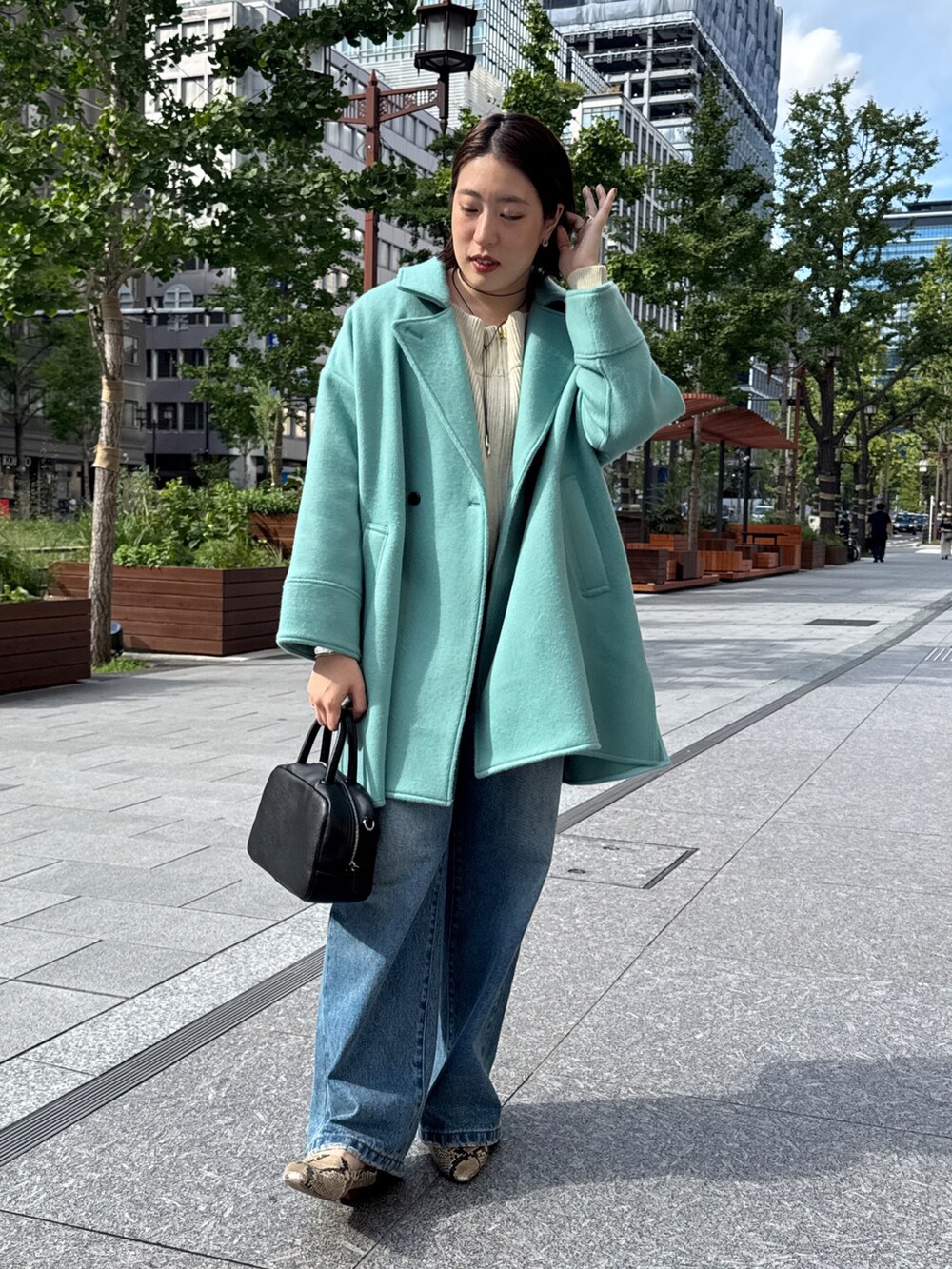 ベージュ系のニット/セーター、グリーン系のその他アウター、ブルー系のデニムパンツを着用したレディースの秋コーディネートの2枚目の写真