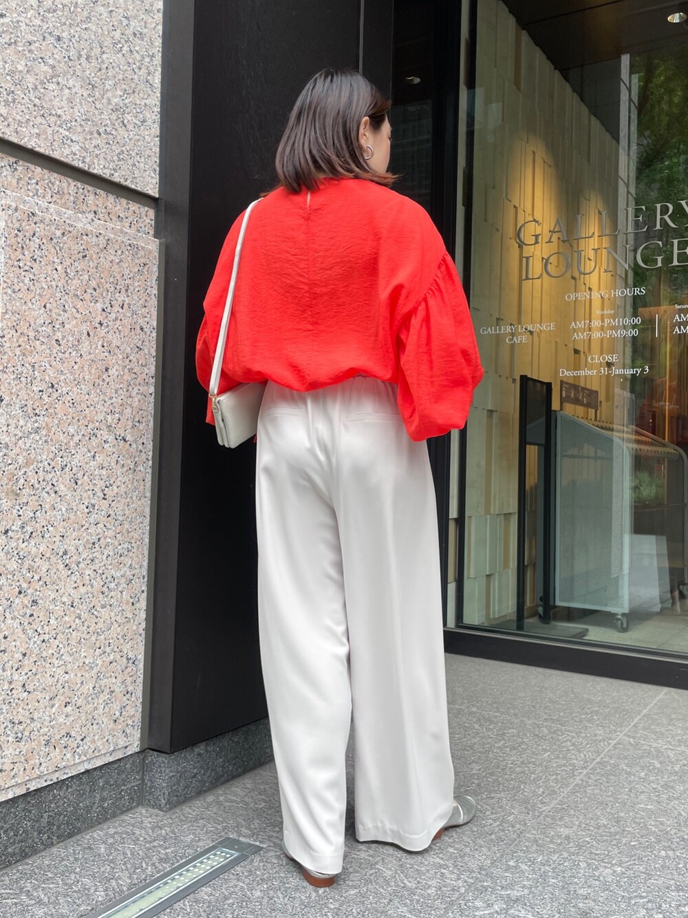 グレー系のスラックス、オレンジ系のシャツ/ブラウス、ホワイト系のショルダーバッグを着用したレディースの春コーディネートの7枚目の写真