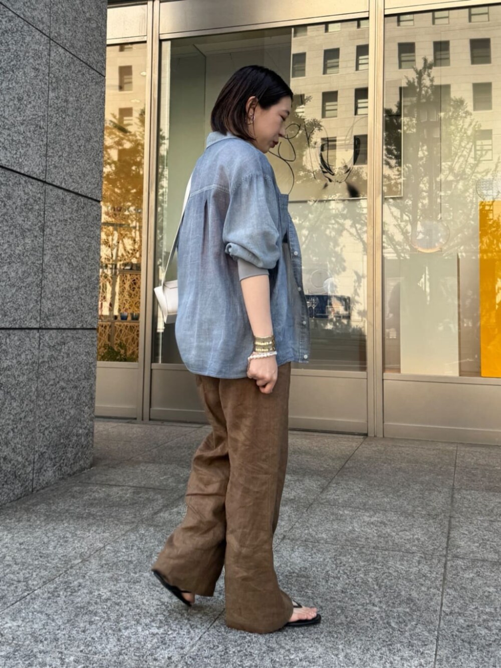 ホワイト系のショルダーバッグ、ブルー系のシャツ/ブラウス、オレンジ系のタンクトップを着用したレディースの春コーディネートの5枚目の写真