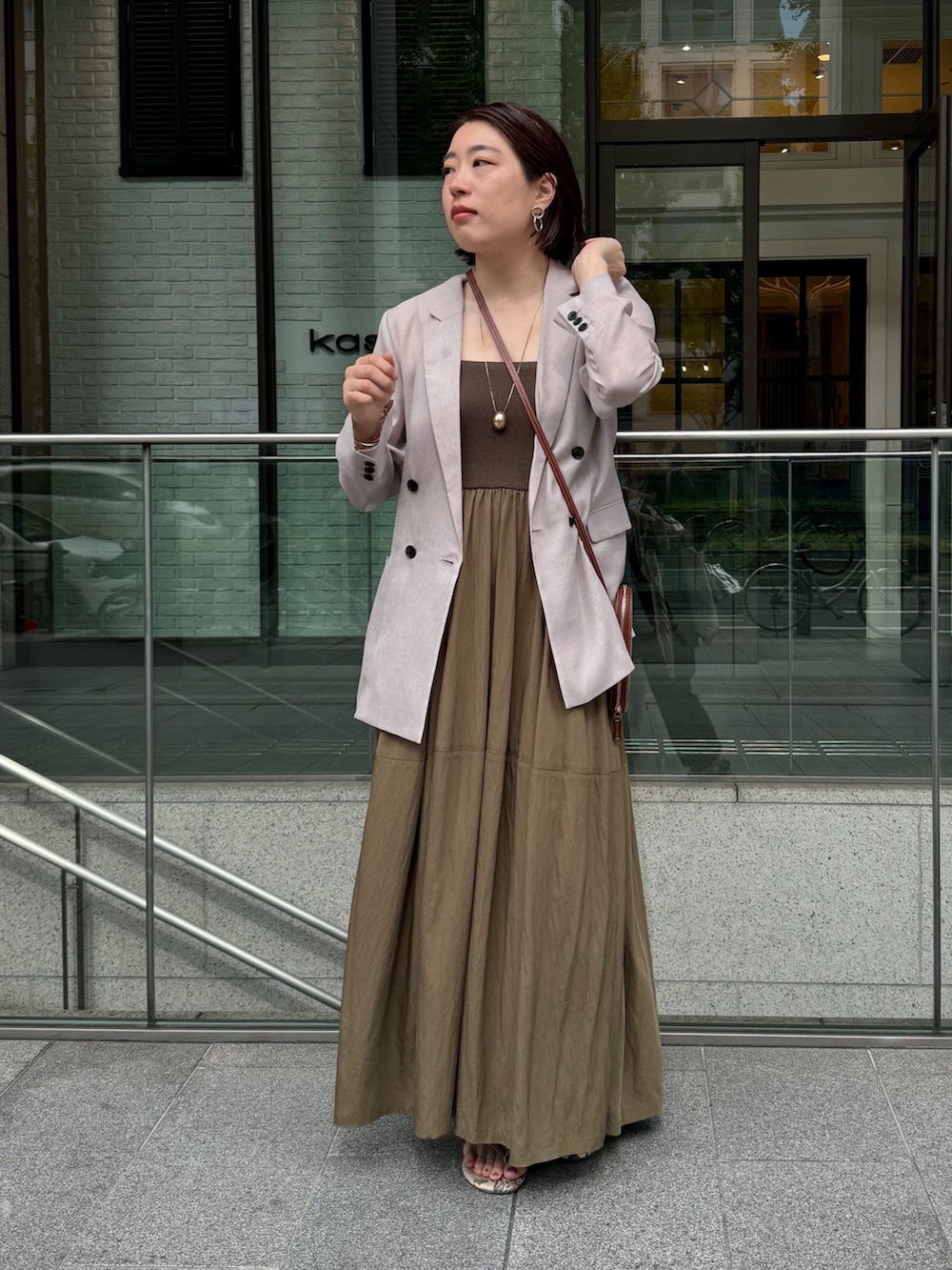 グリーン系のワンピース、ベージュ系のテーラードジャケット、ゴールド系のネックレスを着用したレディースの夏コーディネートの2枚目の写真