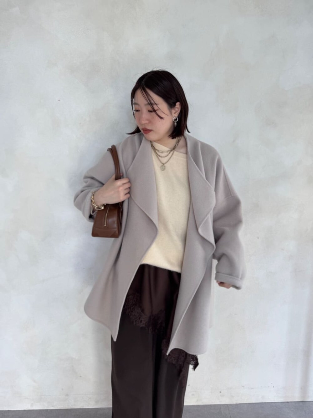 ブラウン系のスラックス、ベージュ系のその他アウター、ブラウン系のキャミソールを着用したレディースの冬コーディネートの4枚目の写真