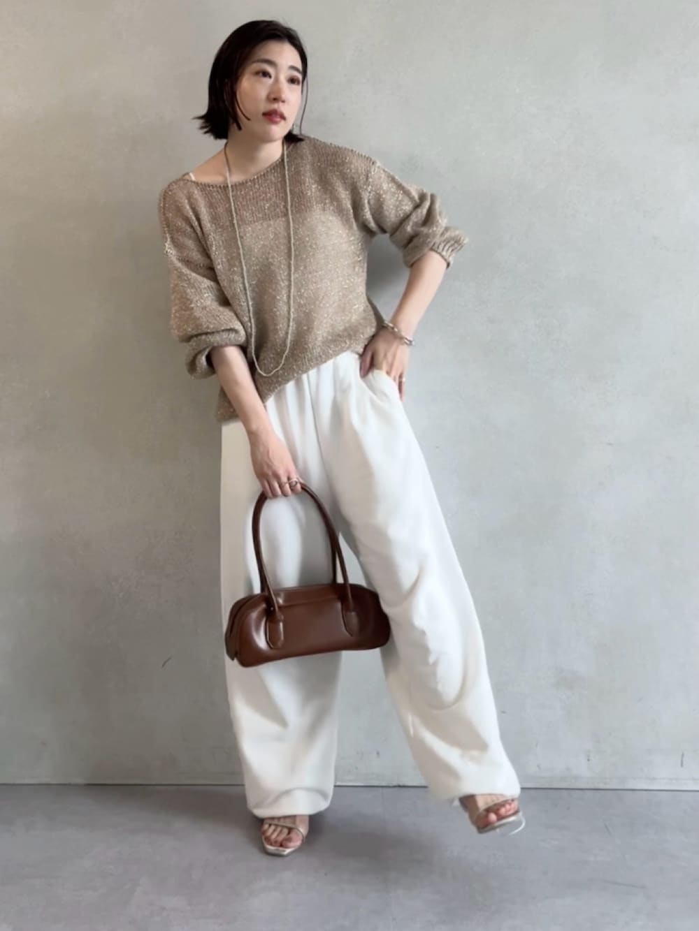ホワイト系のスウェットパンツ、ベージュ系のニット/セーター、ブラウン系のショルダーバッグを着用したレディースの秋コーディネートの2枚目の写真