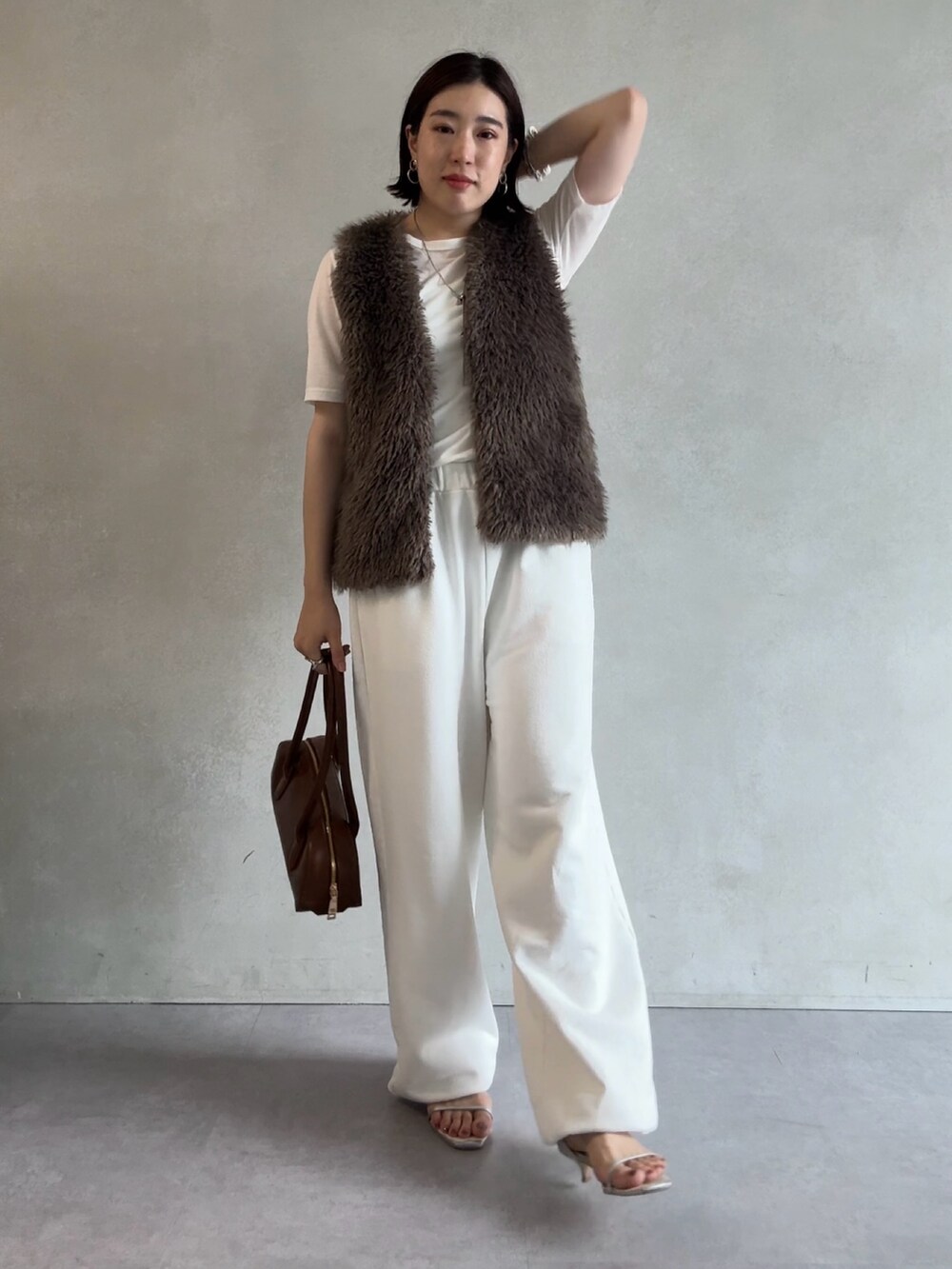 ホワイト系のスウェットパンツ、グレー系のベスト、ブラウン系のショルダーバッグを着用したレディースの秋コーディネートの2枚目の写真