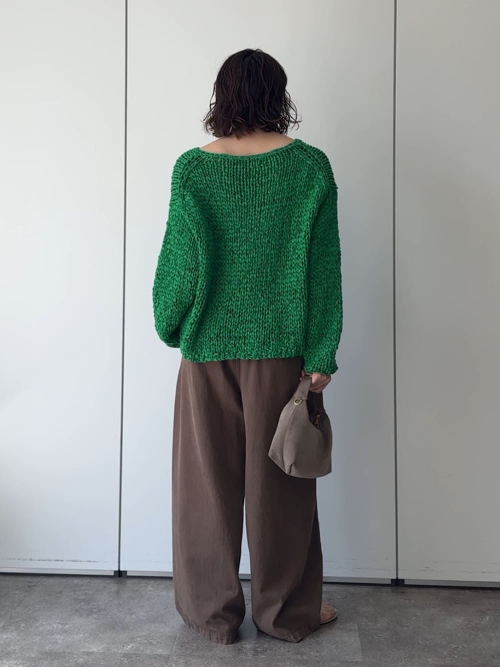 グリーン系のニット/セーター、ブラウン系のデニムパンツ、ブラウン系のネックレスを着用したレディースの秋コーディネートの4枚目の写真