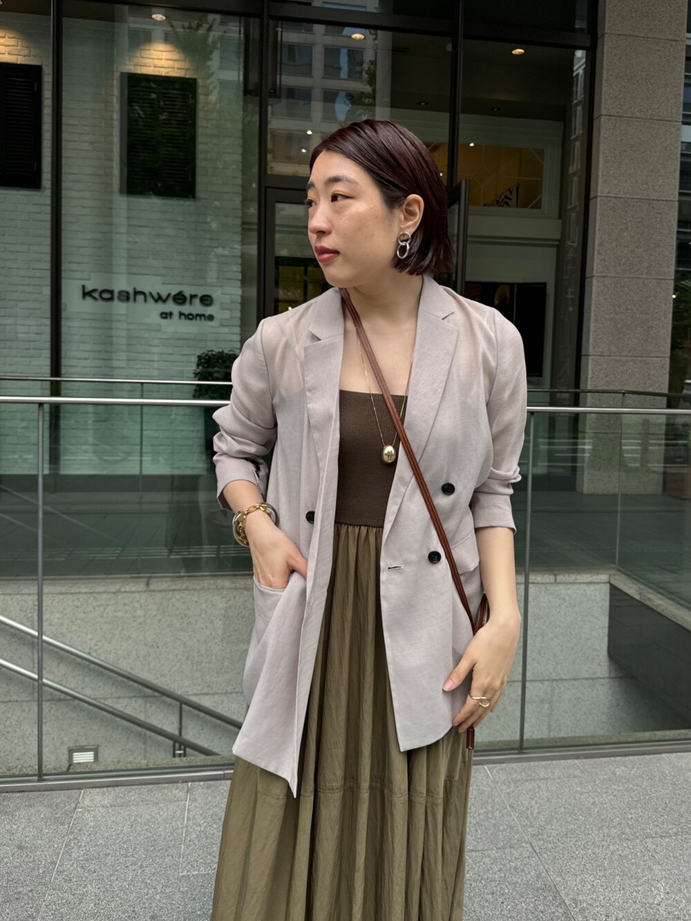 グリーン系のワンピース、ベージュ系のテーラードジャケット、ゴールド系のネックレスを着用したレディースの夏コーディネートの7枚目の写真