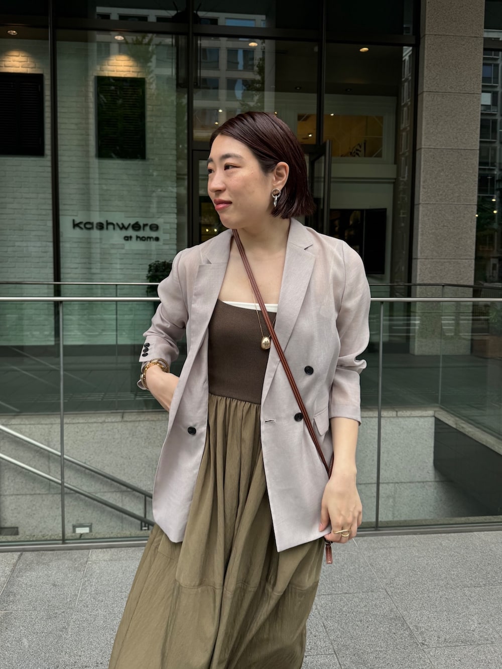 グリーン系のワンピース、ベージュ系のテーラードジャケット、ゴールド系のネックレスを着用したレディースの夏コーディネートの6枚目の写真