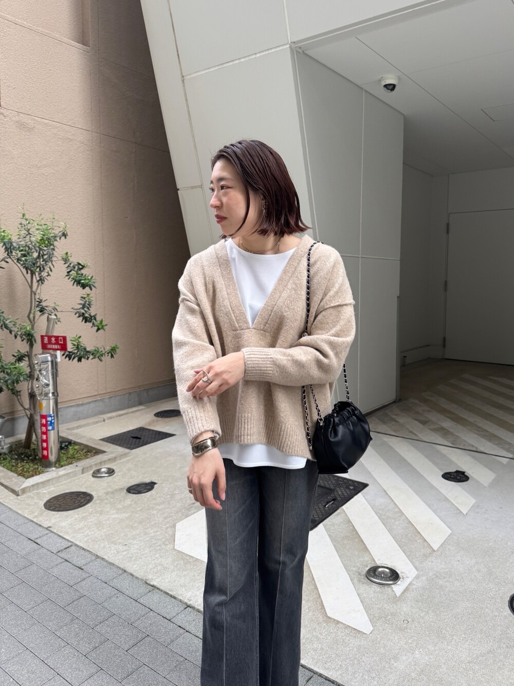 ブラック系のデニムパンツ、ベージュ系のニット/セーター、ホワイト系のTシャツ/カットソーを着用したレディースの秋コーディネートの6枚目の写真