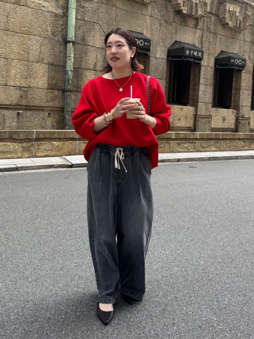 ブラック系のデニムパンツ、ブラウン系のショルダーバッグ、レッド系のニット/セーターを着用したレディースの夏コーディネートの2枚目の写真
